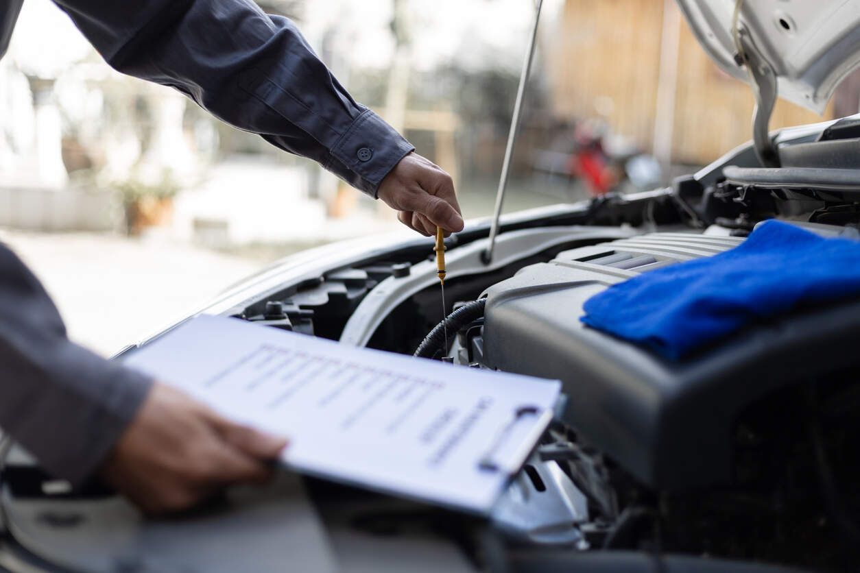 Mechanic inspecting a car engine with a checklist, illustrating California Lemon Law requirements for repair attempts