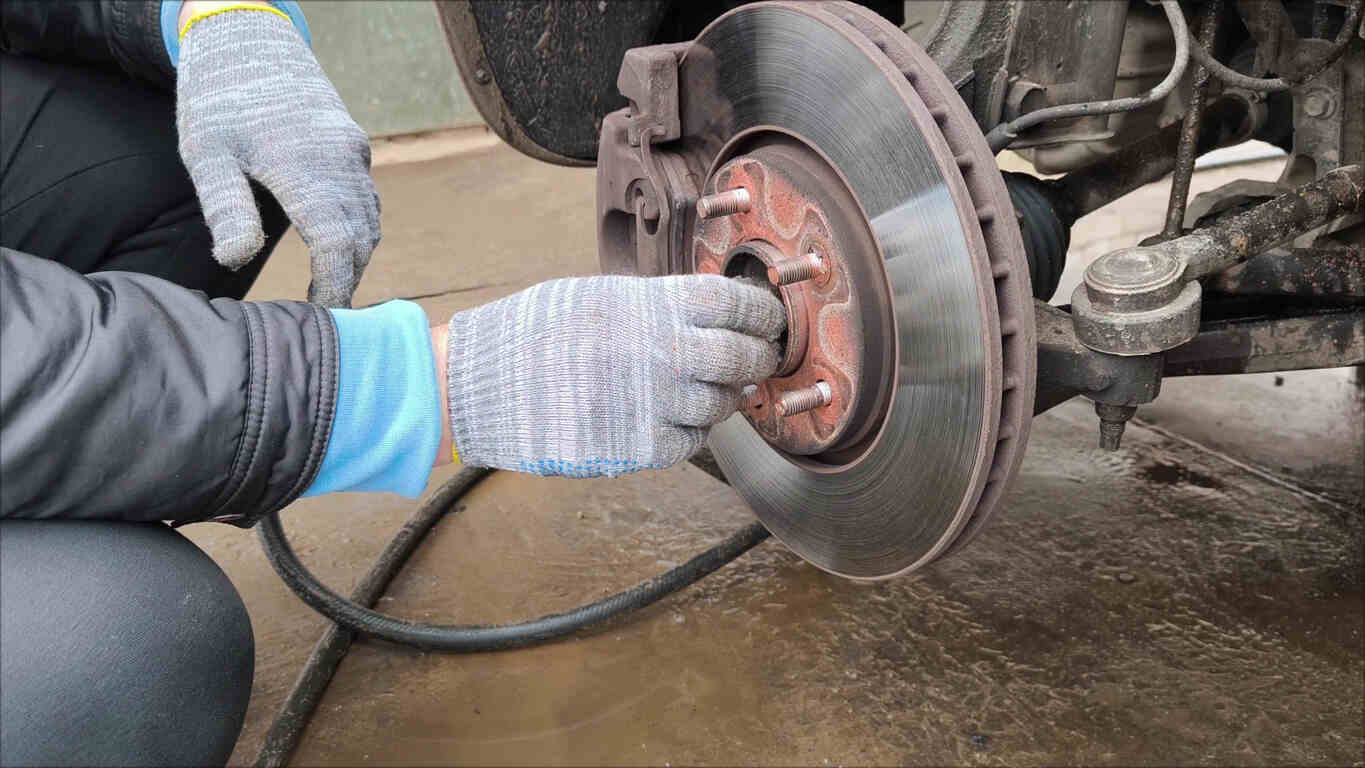 Mechanic inspecting a car's brake disc, symbolizing persistent brake system failures.